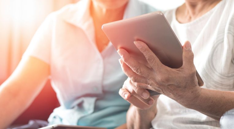 Zwei Personen schauen gemeinsam auf ein Tablet.