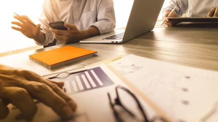 Doctors talk about information at the table with laptop and mobile phone