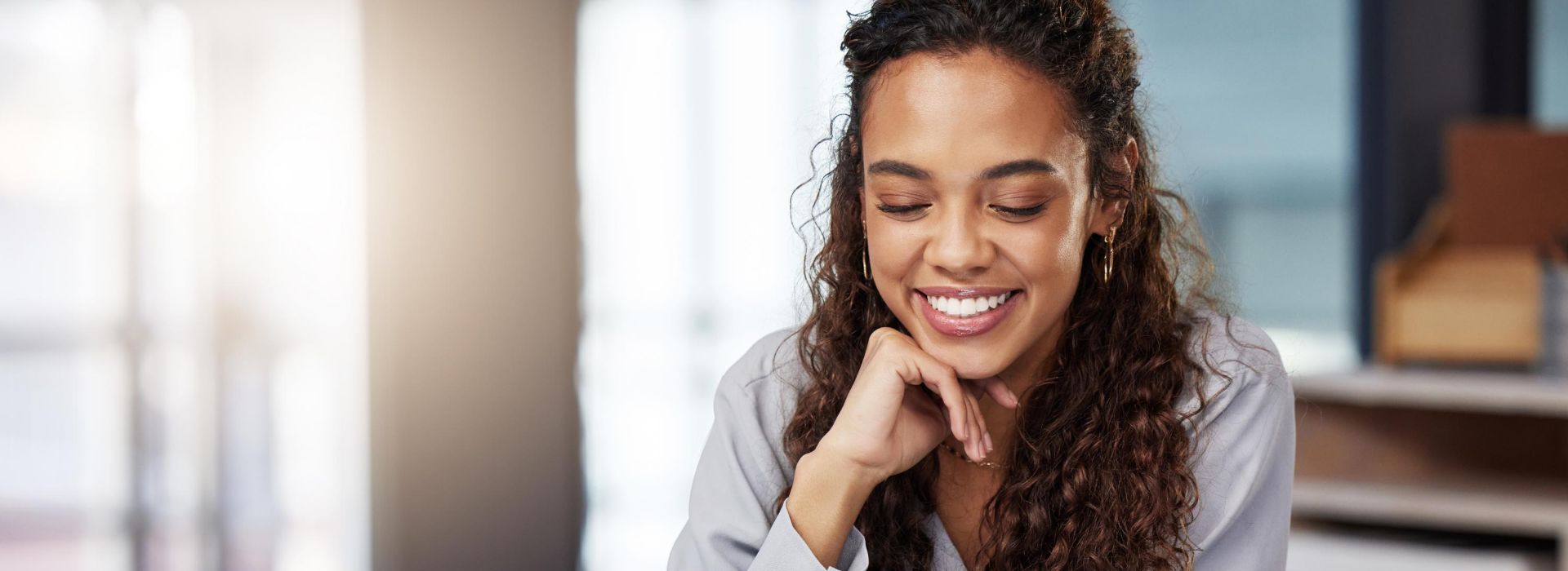 Happy woman at office desk looks at tablet held in her hand