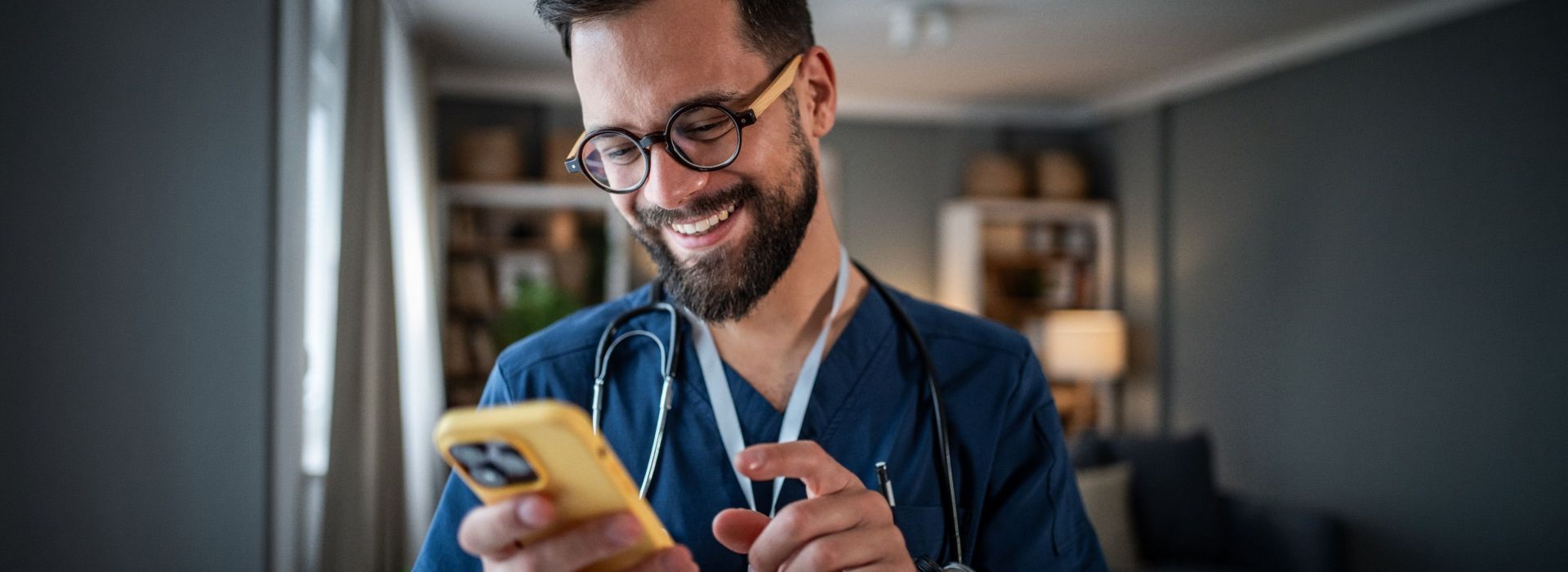 Ein junger Arzt nutzt begeistert den LifeTime Professional Messenger auf seinem Smartphone