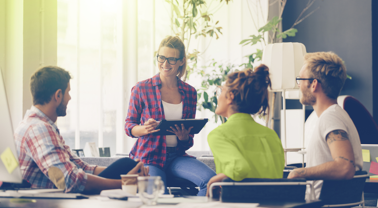 Eine Mitarbeitende sitzt mit drei Kunden im AKQUINET-Büro und berät zum richtigen Umgang mit Unternehmensdaten.