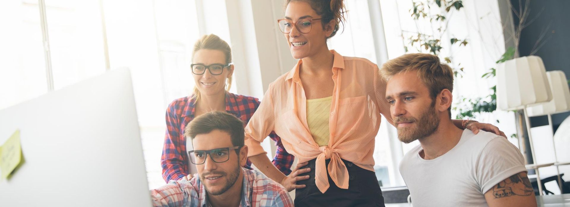 Vier Personen schauen sich Daten vor einem Computerbildschirm an.