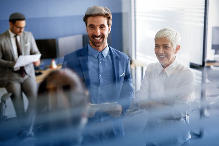 Kunde wird von zwei Microsoft Expert*innen zur Digitalisierung in seinem Vertrieb beraten. Ein Mann überprüft die Costumer Journey im Hintergrund.