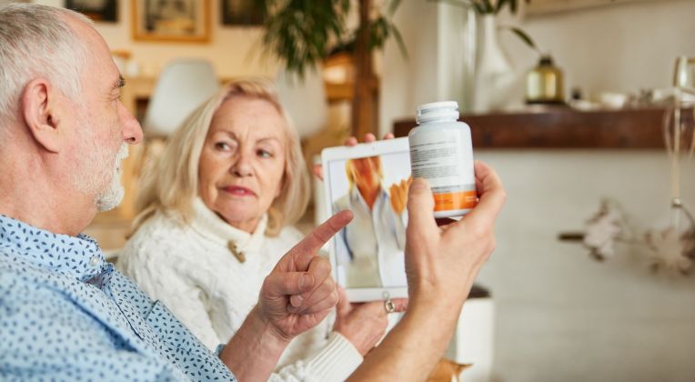 Ein älteres Ehepaar bespricht über kvvideo mit ihrer Ärztin die Messwerte des Mannes