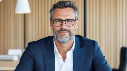 Mann im business Outfit schaut in die Kamera.