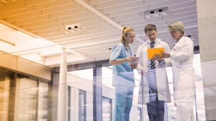 Ein Arzt, eine Ärztin und eine Pflegerin beraten sich in einem Krankenhaus