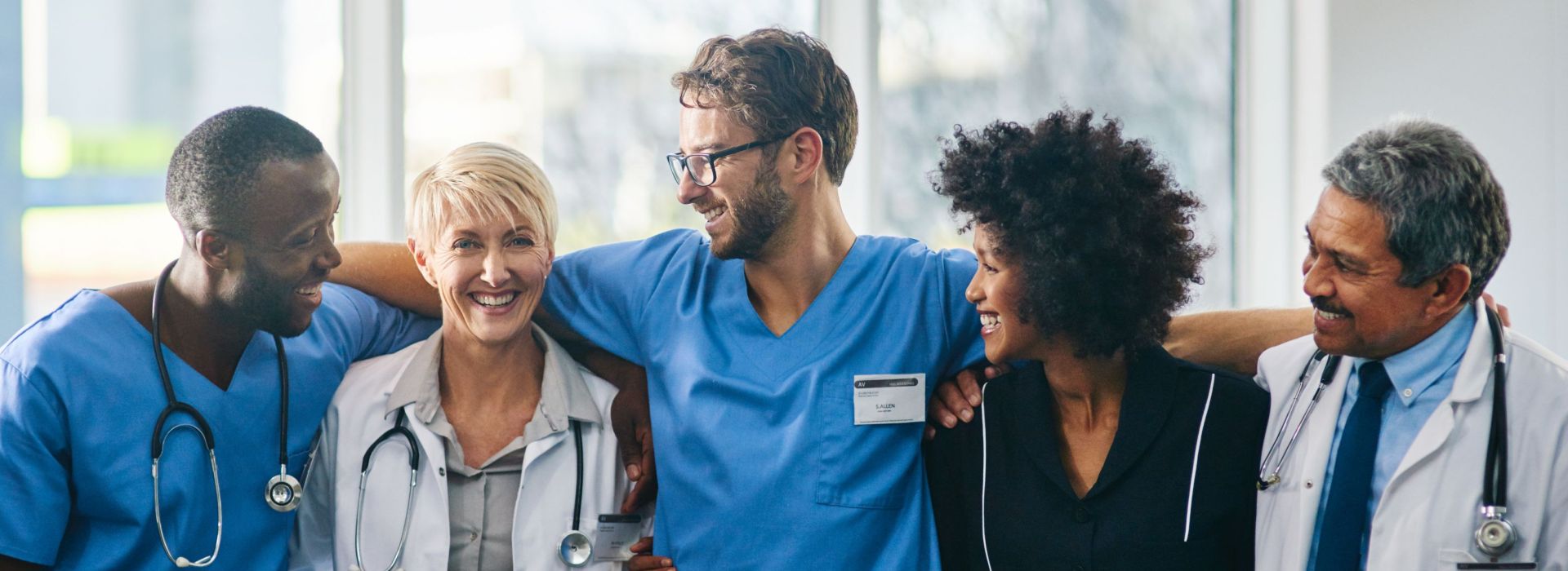 EinTeam aus Ärzten und Pflegern (3 Männer und 2 Frauen) freuen sich zusammen in den Armen liegend über den Support von AKQUINET