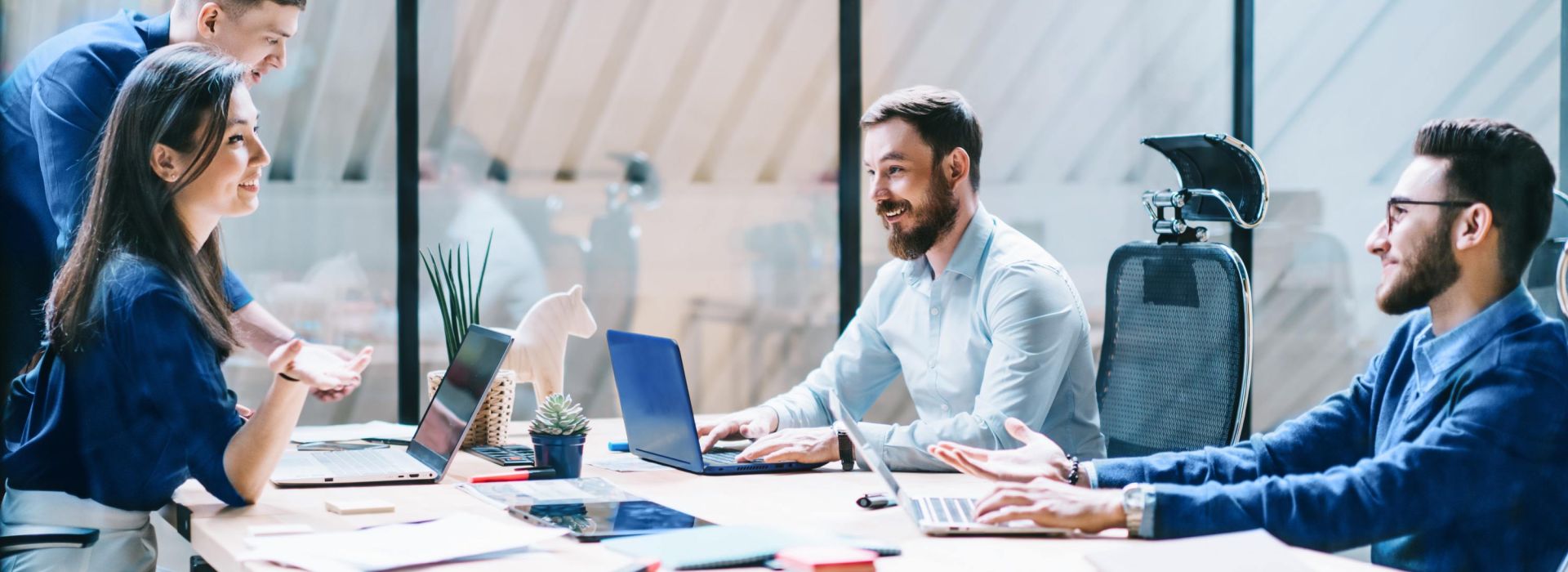Ein Team von Kolleg*innen sitzt gemeinsam an einem Arbeitsplatz und diskutiert Themen.