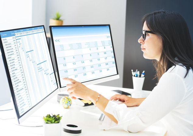 Eine Frau macht auf zwei Bildschirmen einen Datenabgleich für Analysen.