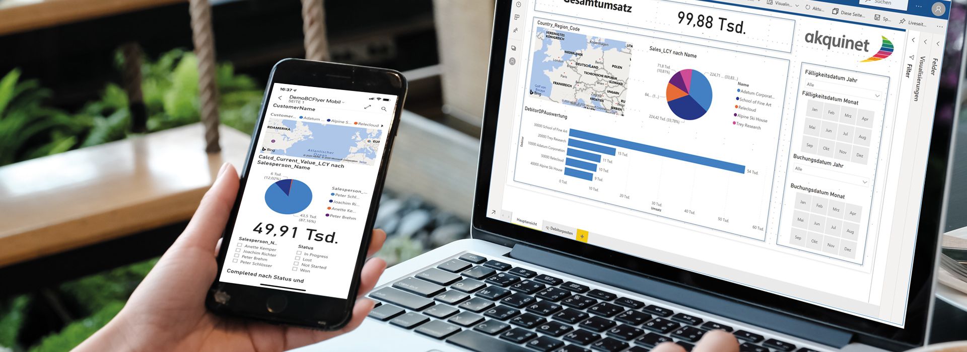 Eine Person sitzt vor einem Laptop, schaut sich ein Power BI Dashboard auf dem Monitor an und vergleicht es mit den Ergebnissen auf einem Handy.