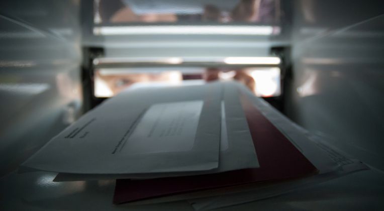 Briefe werden in einen Briefkasten geworfen