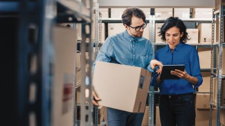 Ein Mann und eine Frau schauen sich in einem Lager den Lagerbestand auf einem Tablet an.
