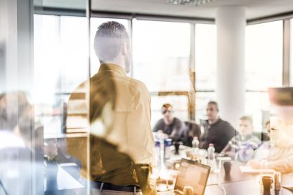 Eine Business Situation in einem Konferenzraum, in dem ein Redner vor einem Team steht.