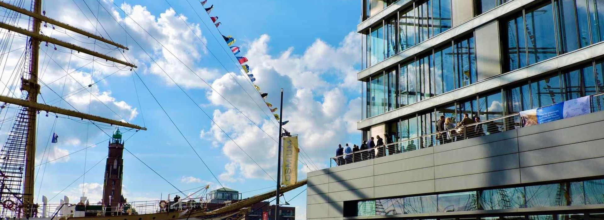 Customers on the roof terrace of the Bremerhaven office with a view of the training ship in the harbor in the best weather during the Maritime Days 2024.