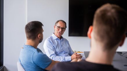 Mitarbeitende von AKQUINET tauschen sich im Meetingraum aus.