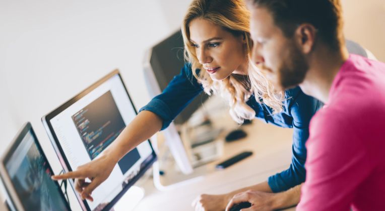 Zwei Personen schauen auf einen Bildschirm und besprechen etwas.