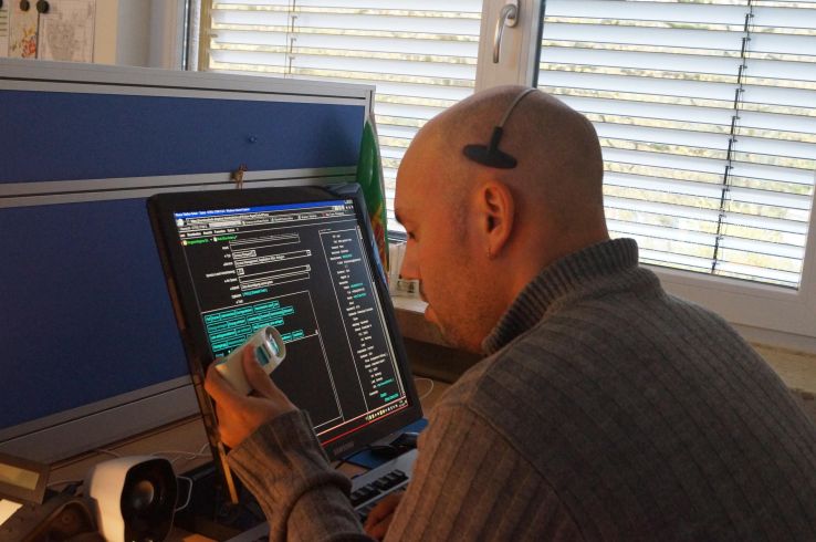 Ein Mitarbeiter der AKQUINET arbeitet aufgrund seiner Sehbehinderung mit Hilfe einer Bildschirmlupe an einem digitalen Arbeitsplatz.