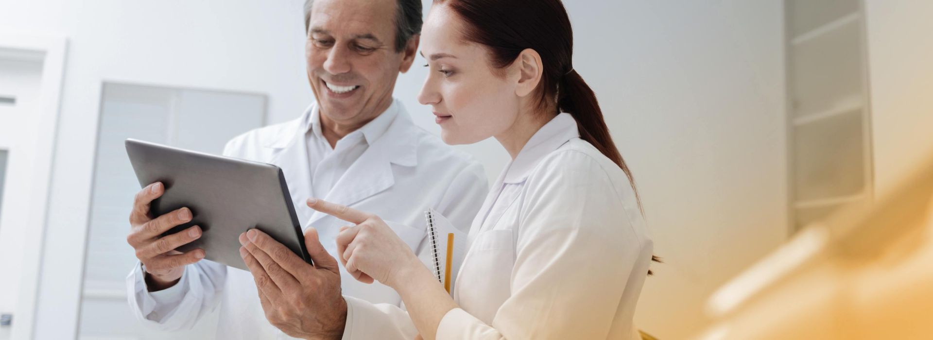 A female doctor and a male doctor look at medical data on a tablet in a good mood